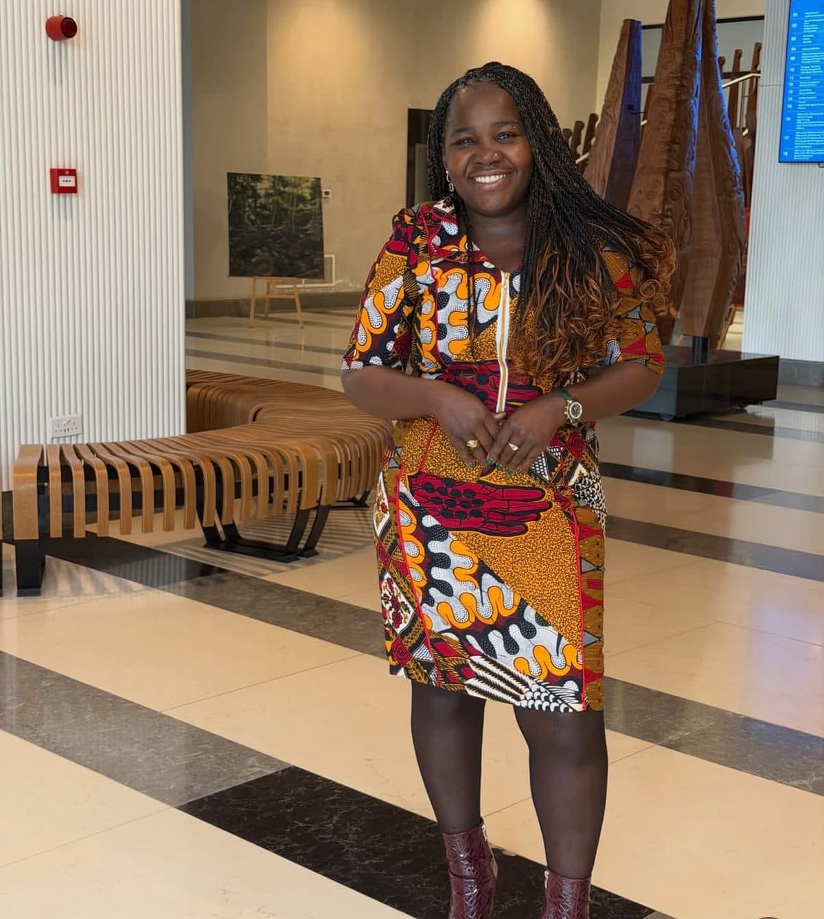 Mundi smiling in a red and gold Ankara zip dress